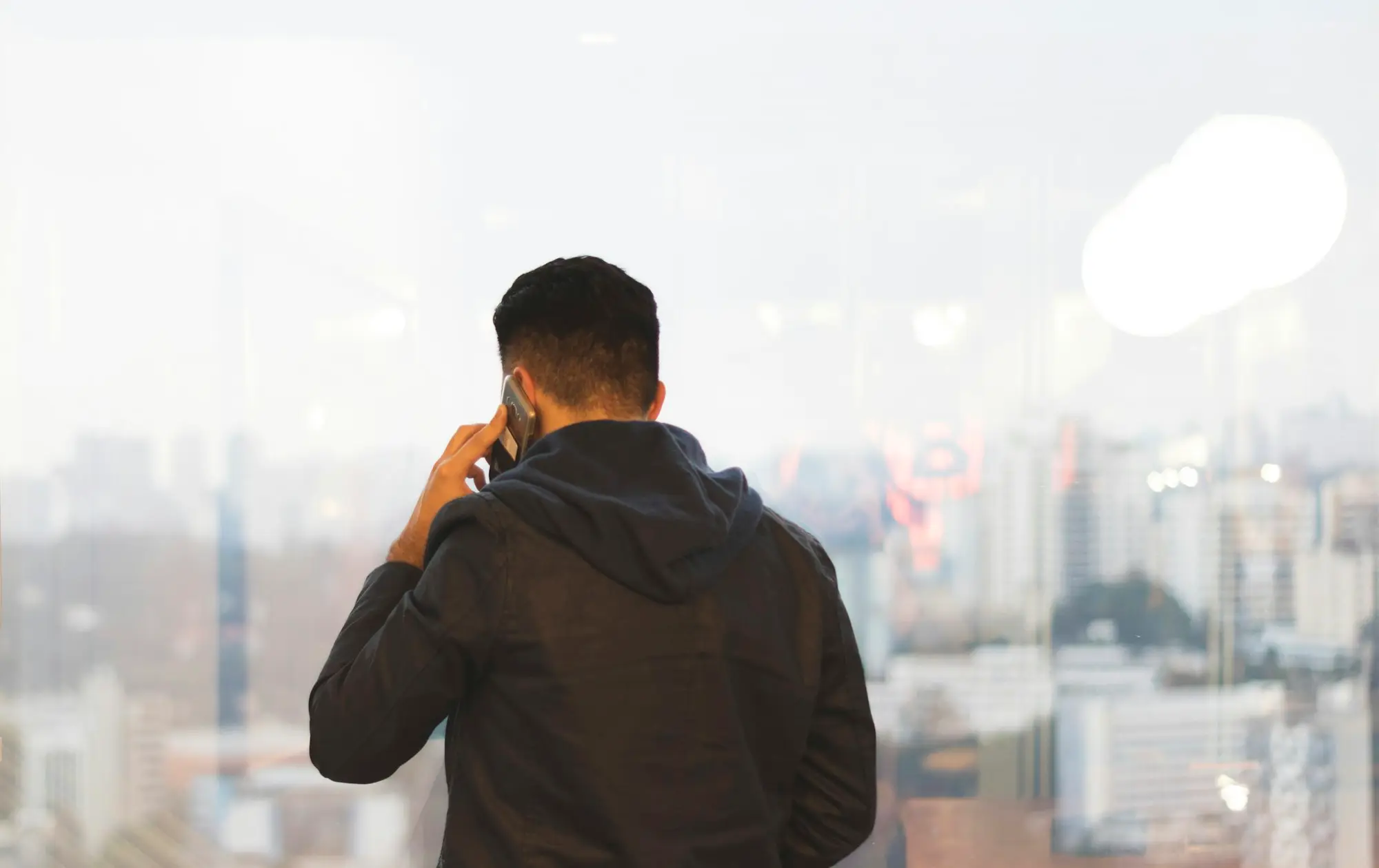 Business owner on the phone at an office window, calling a lender to ask which lending criteria his application missed